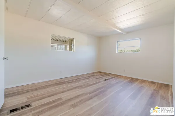 an empty room with wooden floor and windows