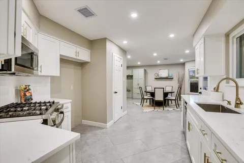 a kitchen with stainless steel appliances a sink a stove a microwave a counter top space and cabinets