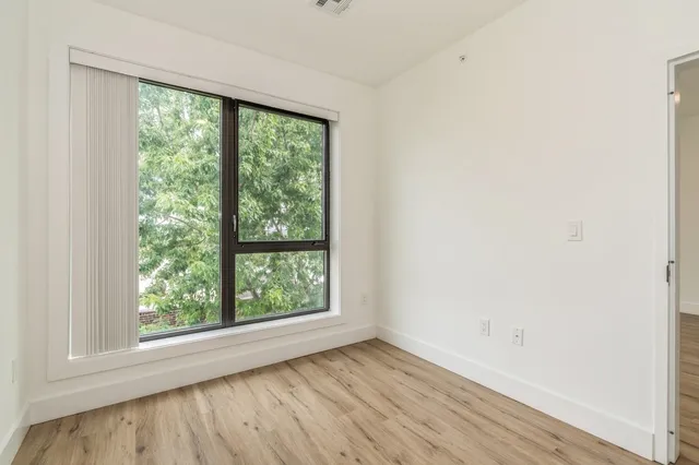 an empty room with wooden floor and windows