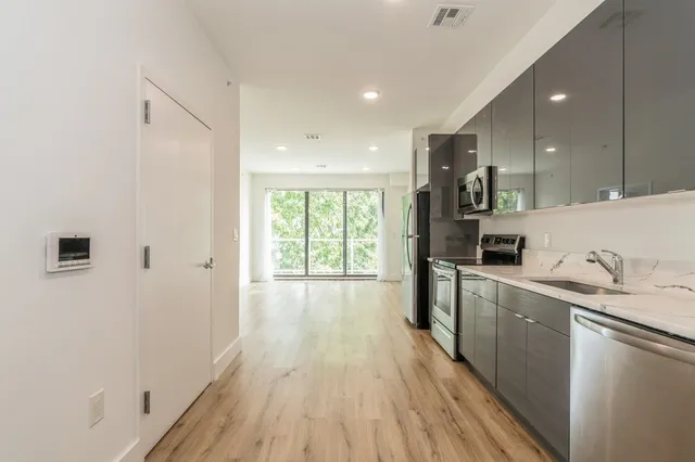 a kitchen with granite countertop a stove a sink a refrigerator and wooden floor