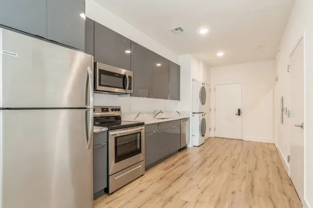 a kitchen with stainless steel appliances a refrigerator a sink and white cabinets