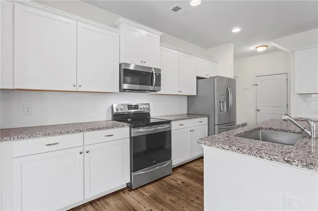 a kitchen with granite countertop white cabinets and stainless steel appliances