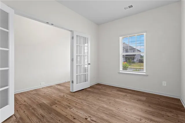 an empty room with wooden floor and windows
