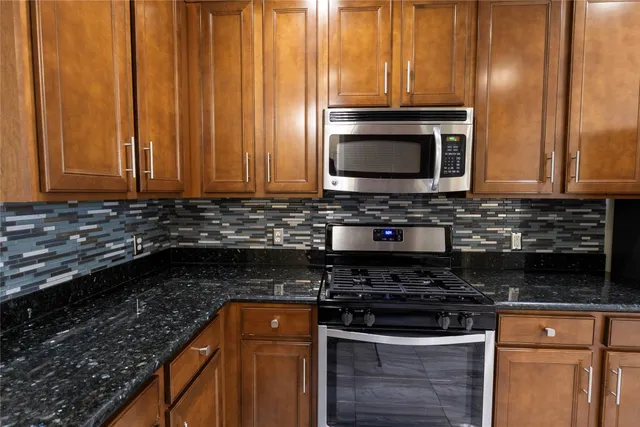 a kitchen with granite countertop a stove top oven cabinetry a sink and a window