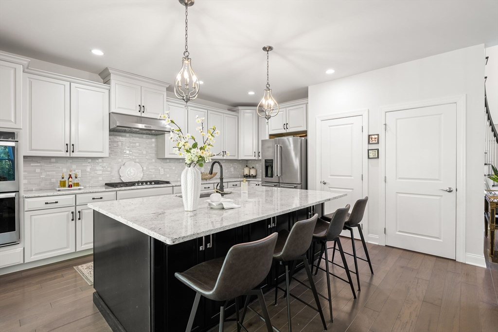 2 Hummingbird Way, Unit 1 Methuen, MA 01844 - Photo 15 of 42 a kitchen with stainless steel appliances kitchen island granite countertop a dining table chairs and white cabinets