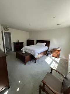 a bedroom with a bed chair and a mirror