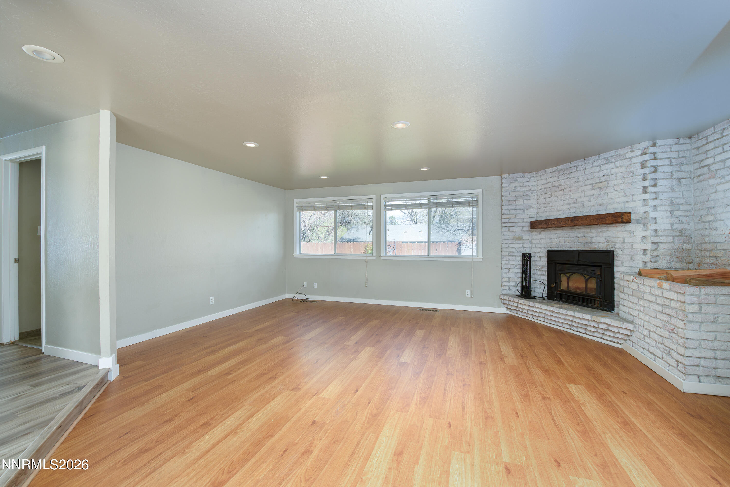 901 Sharrow Way Carson City, NV 89703 - Photo 7 of 45 an empty room with wooden floor fireplace and windows