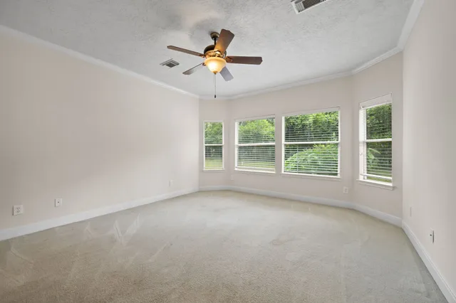 an empty room with windows and fan