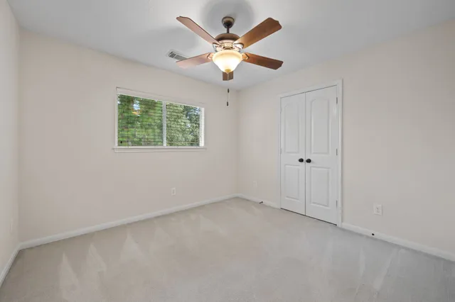 an empty room with windows and ceiling fan