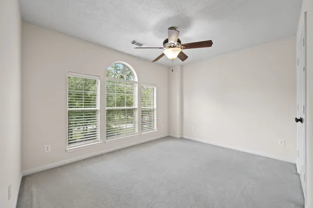 an empty room with windows and ceiling fan