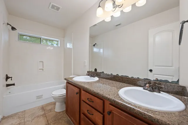 a bathroom with a granite countertop sink a toilet a mirror and shower