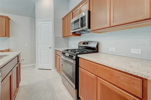 a kitchen with stainless steel appliances granite countertop a sink a stove and a refrigerator