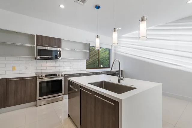 a kitchen with stainless steel appliances kitchen island granite countertop a refrigerator and a stove top oven