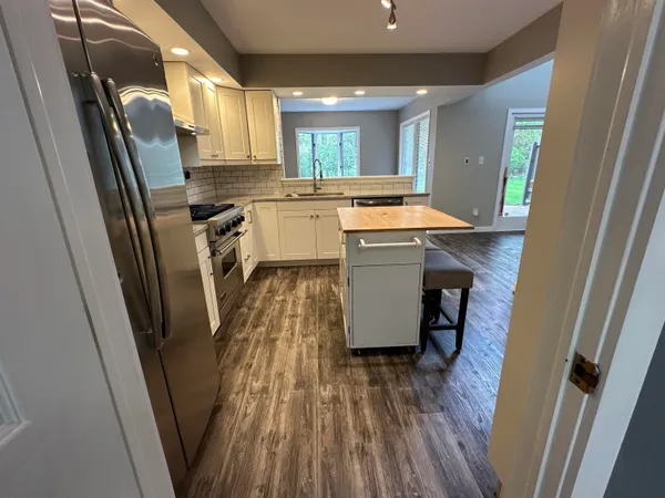 a kitchen with refrigerator a sink and wooden floor