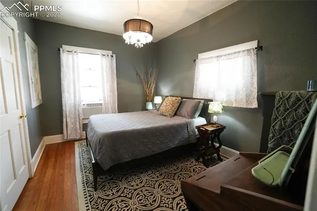 a bedroom with a bed and dresser with wooden floor