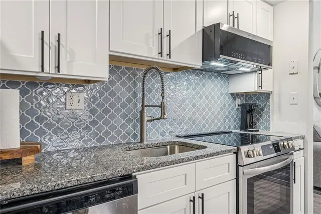 a kitchen with granite countertop a sink a stove and cabinets