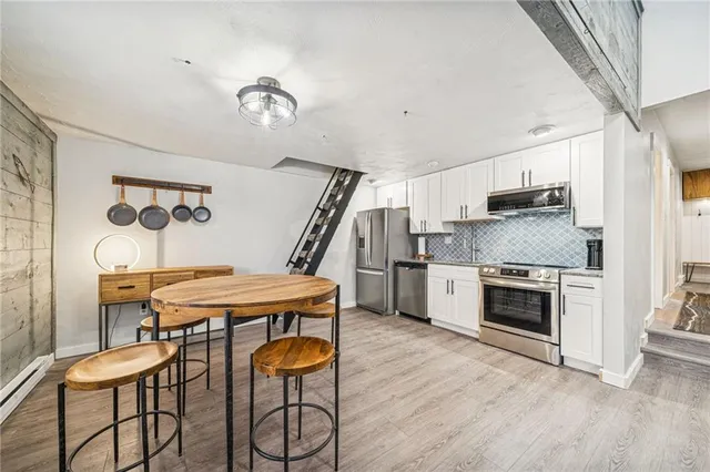 a kitchen with stainless steel appliances a stove a refrigerator and a fireplace