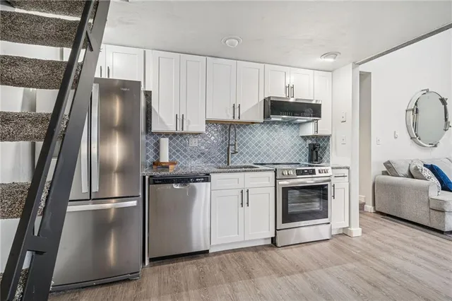 a kitchen with stainless steel appliances granite countertop a refrigerator a stove a sink and a granite countertops with wooden floor