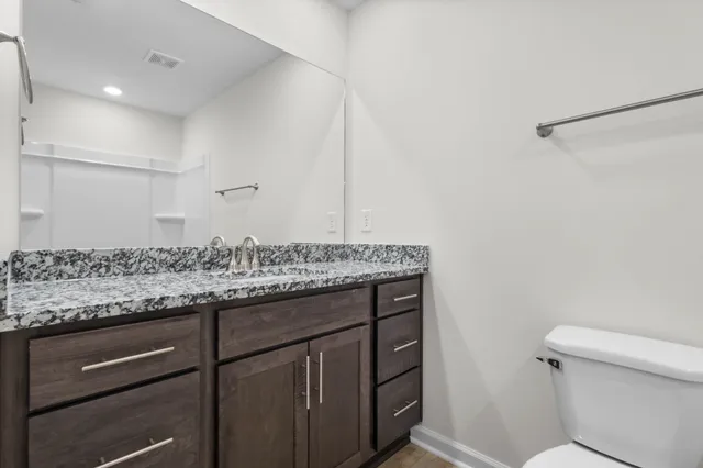 a bathroom with a granite countertop sink and a toilet