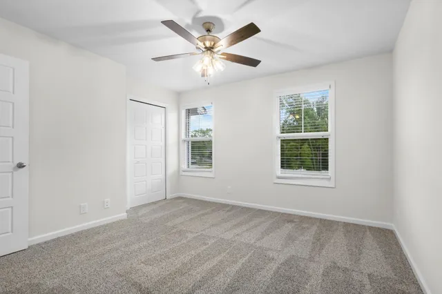an empty room with ceiling fan and windows