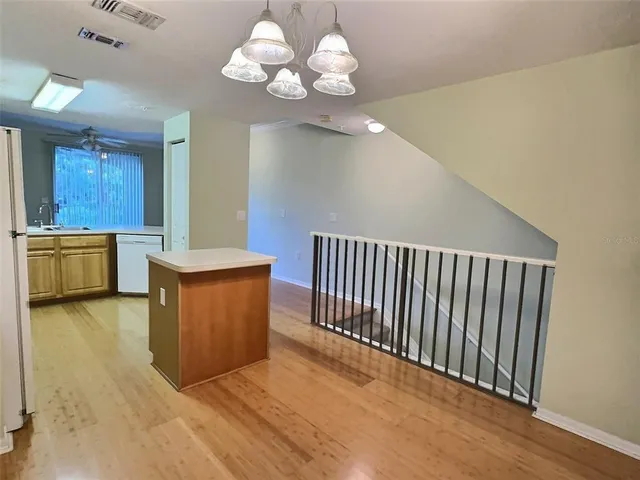 a view of a kitchen with a stove wooden cabinet wooden floor and chandelier