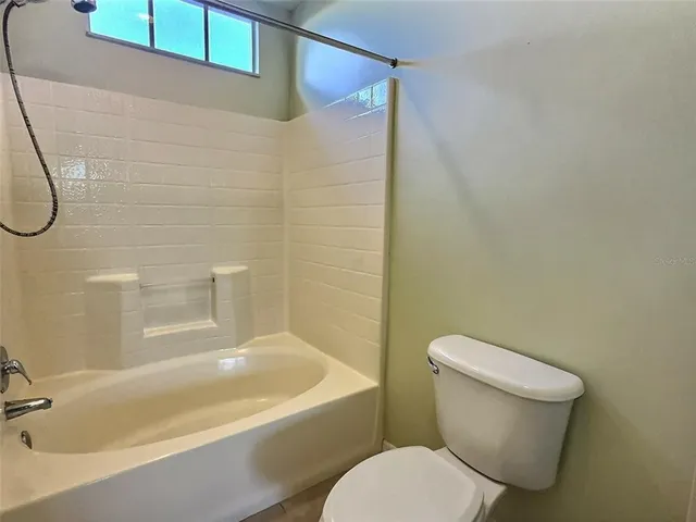 a white toilet sitting next to a bath tub and a shower