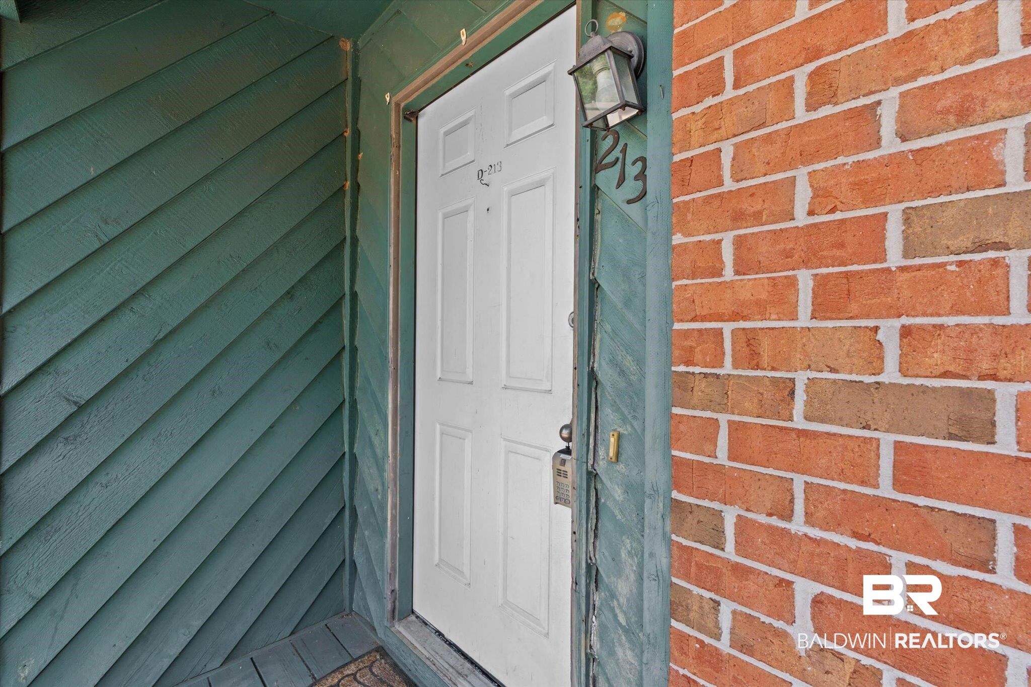 500 Grant Street, Unit D213 Daphne, AL 36526 - Photo 2 of 6 Entryway featuring a white paneled door, brick exterior, and diagonal wood siding
