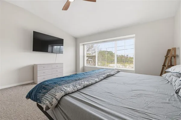 a bedroom with a bed a flat screen tv and a window