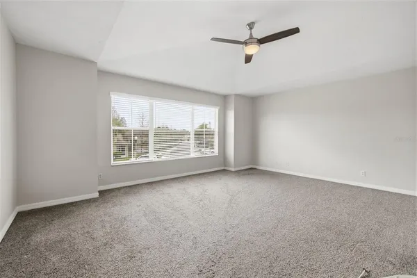 an empty room with ceiling fan and windows