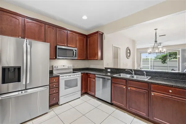 a white kitchen with granite countertop stainless steel appliances and a sink
