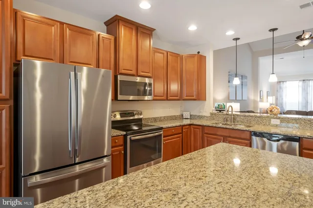 a kitchen with stainless steel appliances granite countertop a refrigerator a sink dishwasher a stove and a refrigerator with wooden floor