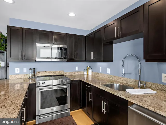 a kitchen with stainless steel appliances granite countertop a stove a sink and a microwave