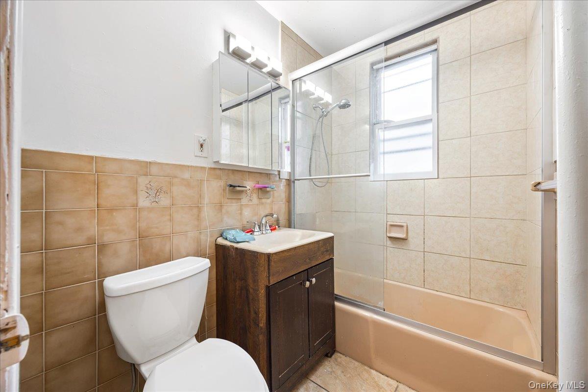 2953 Harding Avenue Bronx, NY 10465 - Photo 12 of 29 Full bathroom with vanity, enclosed tub / shower combo, and tile walls