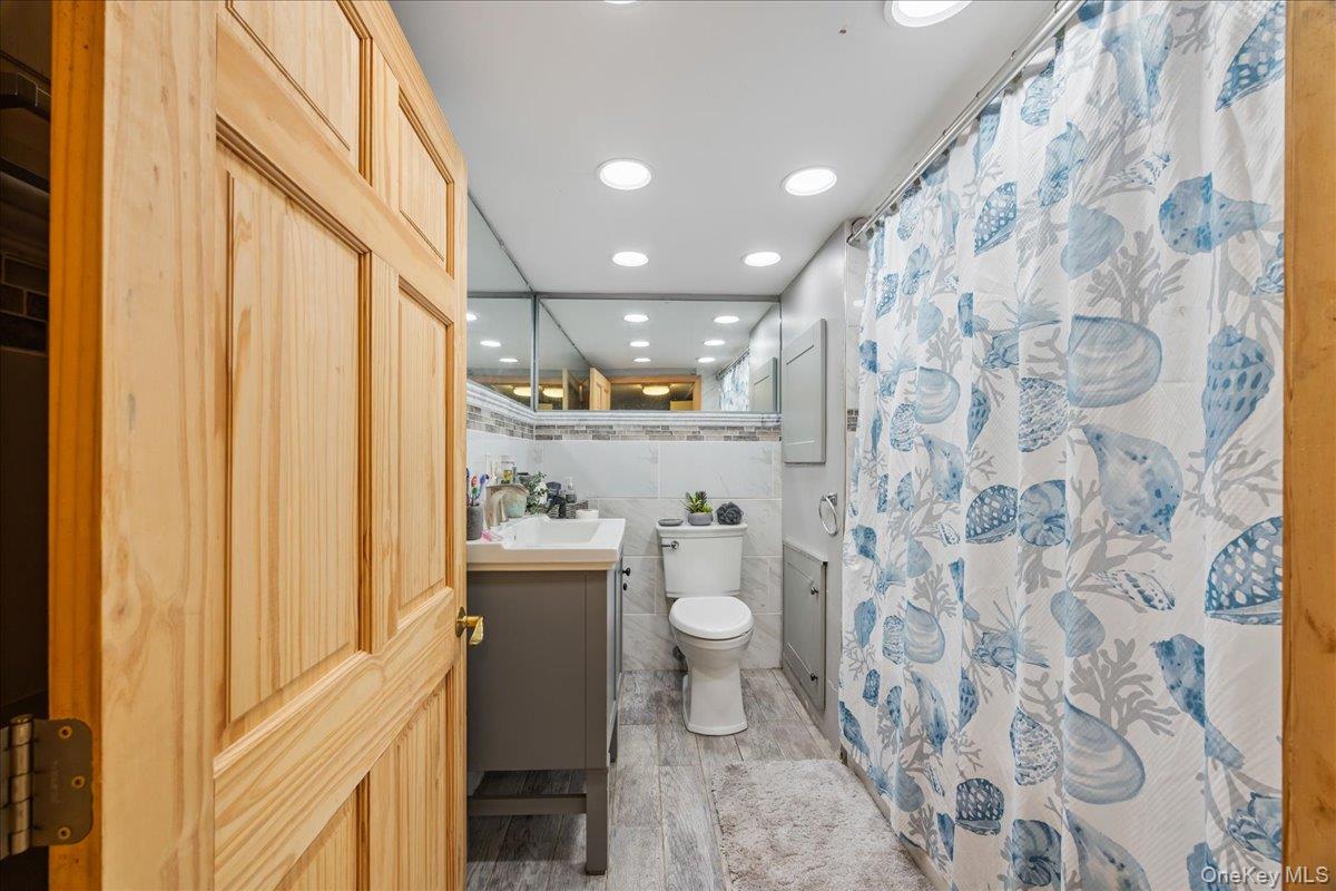 2953 Harding Avenue Bronx, NY 10465 - Photo 19 of 29 Full bathroom with vanity, tile walls, a shower with curtain, and recessed lighting