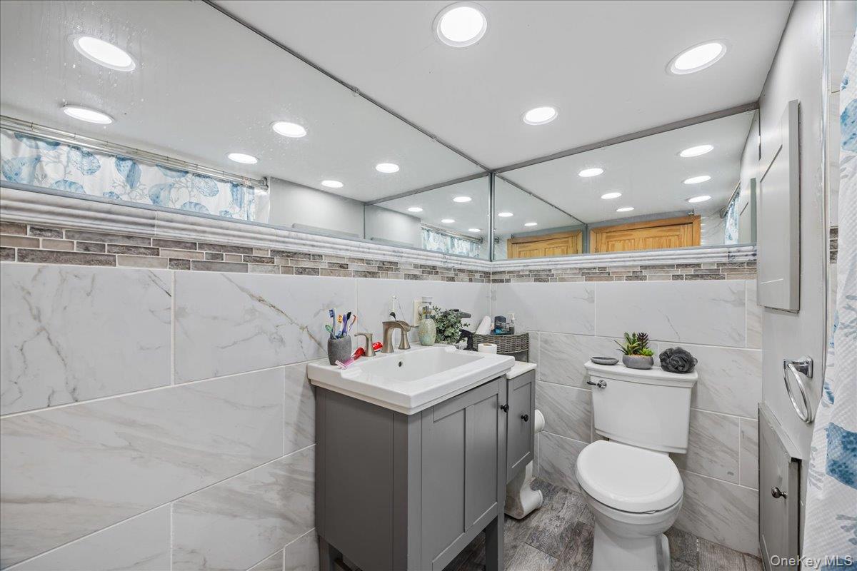 2953 Harding Avenue Bronx, NY 10465 - Photo 20 of 29 Full bathroom with vanity, a shower with shower curtain, recessed lighting, and tile walls