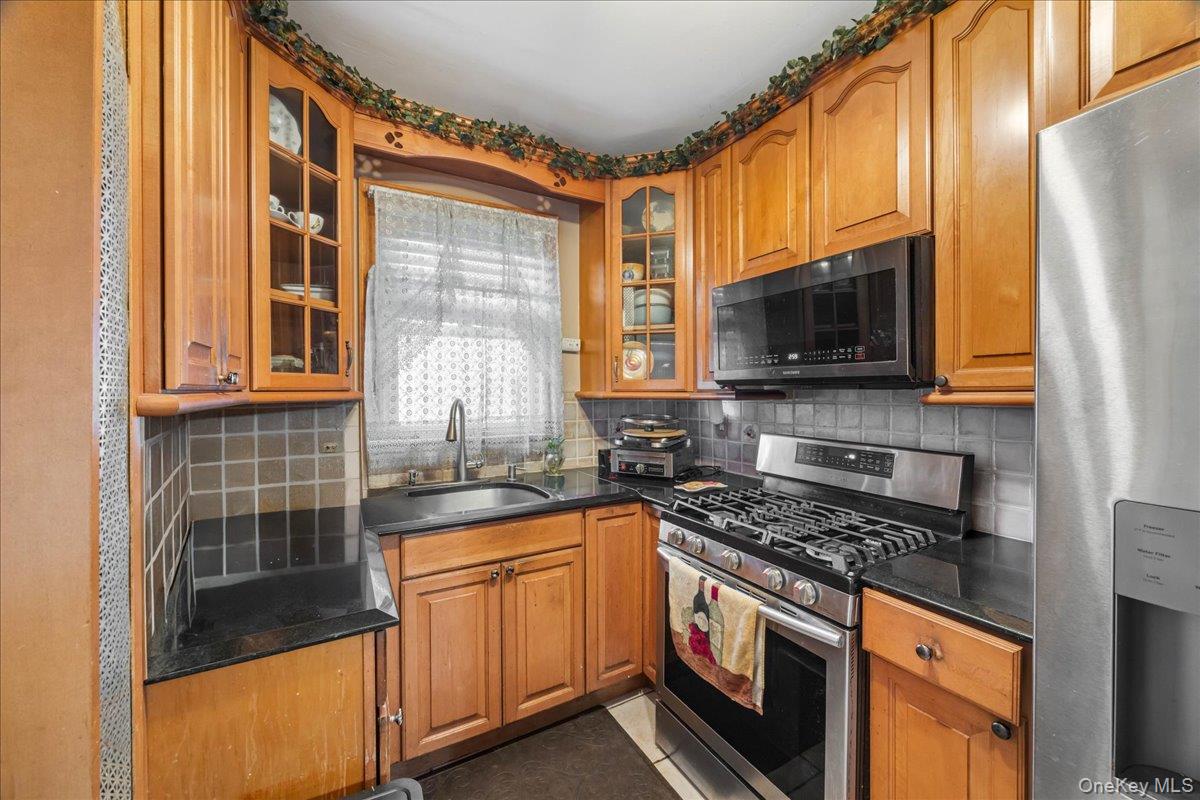 2953 Harding Avenue Bronx, NY 10465 - Photo 7 of 29 Kitchen featuring appliances with stainless steel finishes, brown cabinets, and backsplash