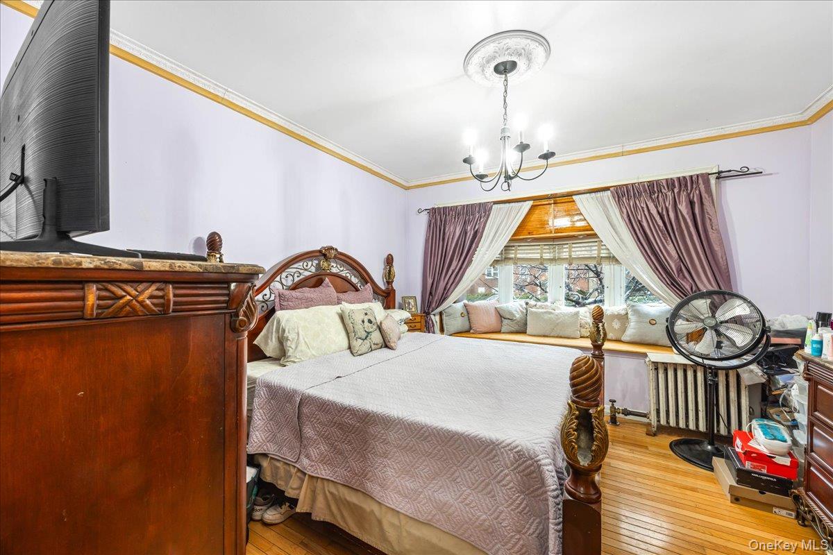 2953 Harding Avenue Bronx, NY 10465 - Photo 9 of 29 Bedroom featuring wood-type flooring, ornamental molding, and a chandelier