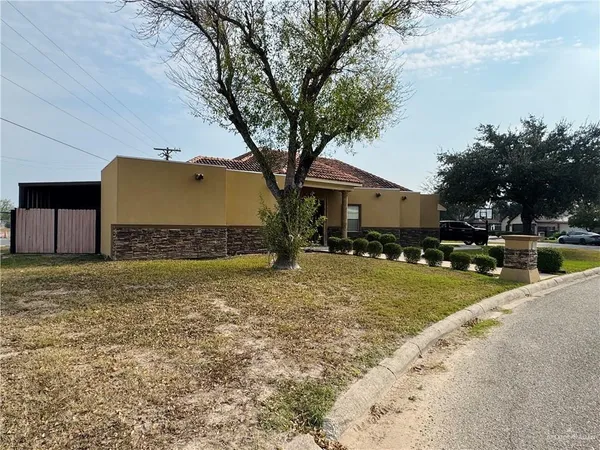 a front view of a house with a garden and tree