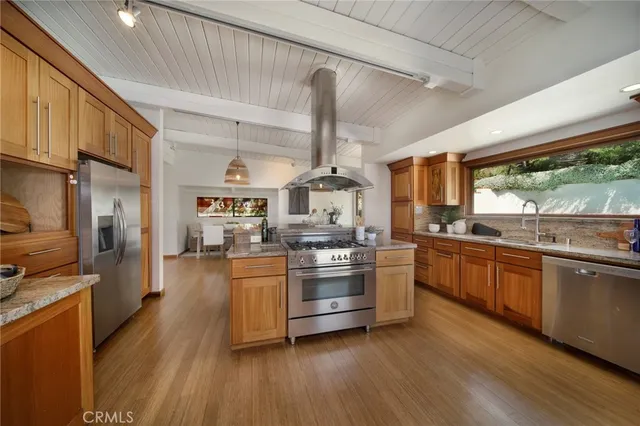 a kitchen with stainless steel appliances granite countertop hardwood floor sink stove dining table chairs and granite counter top