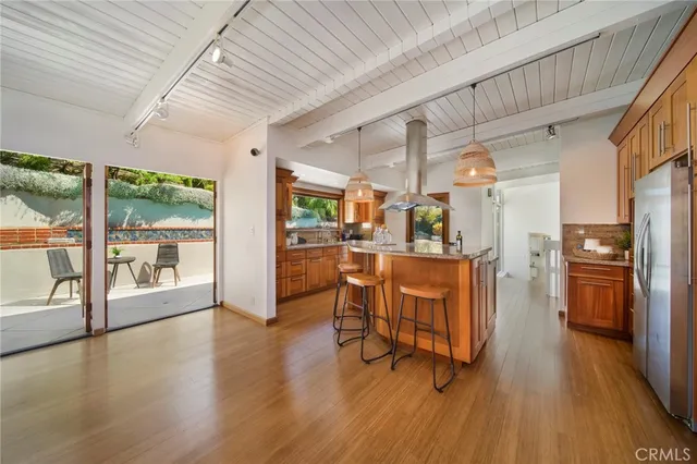 a living room with stainless steel appliances kitchen island hardwood floor and a large window