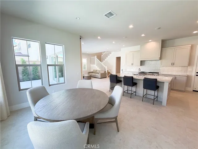 a living room with stainless steel appliances furniture a dining table and chairs