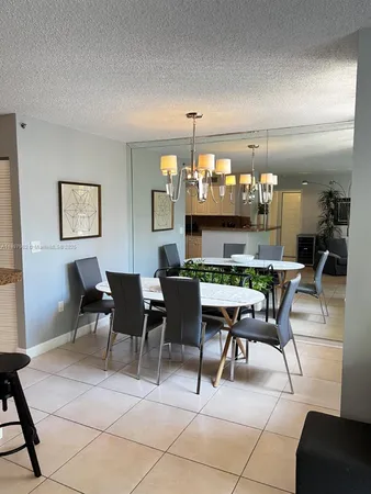 a dining room filled a chandelier and kitchen view