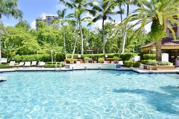 a front view of a house with swimming pool and trees in the background