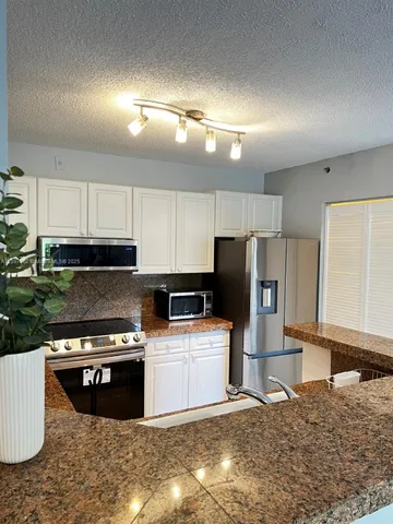 a kitchen with granite countertop a sink stainless steel appliances and cabinets