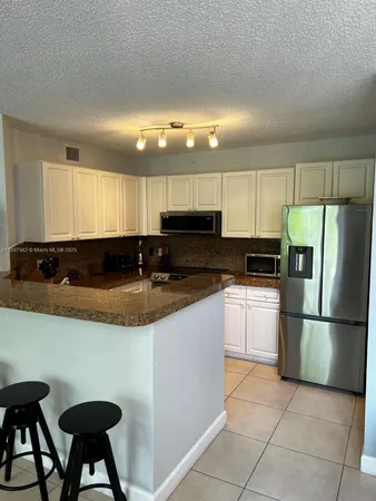 a kitchen with granite countertop a sink and white cabinets
