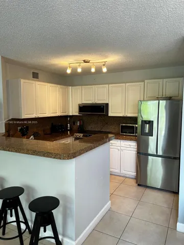 a kitchen with granite countertop a sink and white cabinets