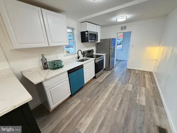a kitchen with wooden floors and stainless steel appliances