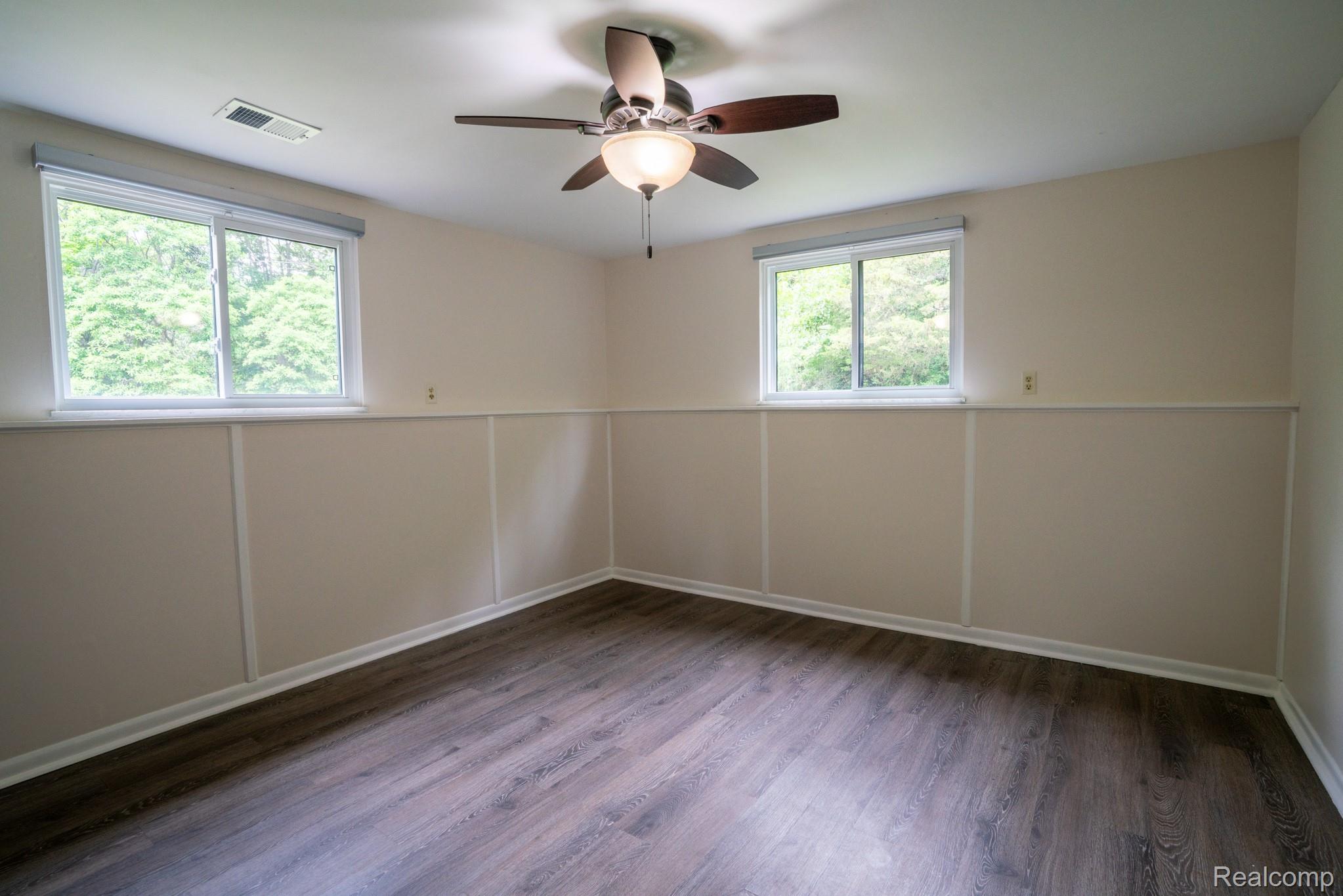 7333 Toma Road Dexter, MI 48130 - Photo 34 of 45 Room featuring wood-finish flooring, two windows, wainscoting, and a ceiling fan with integrated lighting