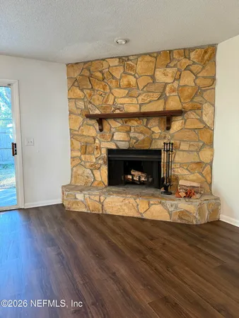 a view of empty room with wooden floor and fireplace