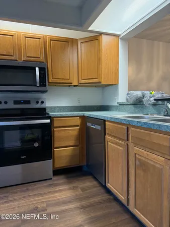 a kitchen with granite countertop a stove top oven microwave and cabinets